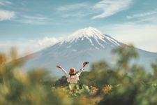 Happy tourist traveler woman enjoying with open arms on lake kawaguchiko with mount fuji in japan, spring and summer, Japan travel vacation.