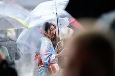 Seorang perempuan yang memakai kimono sedang berjalan saat hari sedang hujan di Kuil Sensoji, Asakusa, Tokyo, (26/3/2024). (AFP/PHILIP FONG)