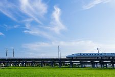 Ilustrasi shinkansen sedang melaju dengan latar belakang langit biru.