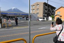 Turis mengambil foto di depan Lawson dengan pemandangan Gunung Fuji pada Mei 2024.