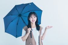 Seorang wanita mengenakan kaos yang dipadupadankan denganouter sedang memakai payung.