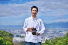 Seorang pria mengenakan kemeja lengan panjang sedang memotret.