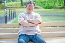 Seorang pria mengenakan outfit sweater dengan capuchon.