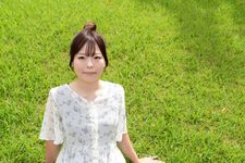 Seorang wanita dengan outfit blus sedang bersantai di taman.
