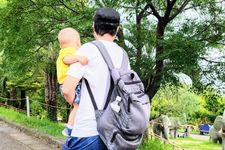 Seorang pria mengenakan outfit kaos sedang menggendong anak.