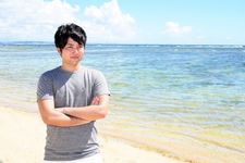 Seorang pria mengenakan outfit kaos sedang bersantai di pantai.
