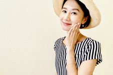 Seorang wanita mengenakan outfit blus dengan memakai topi.