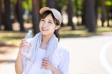 Seorang wanita memakai outfit kaos dan memakai topi sedang berolahraga.