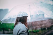 Seorang wanita memakai blazer dan payung bening.