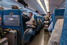 Seorang pramugari mendorong gerobak makanan ringan di lorong kereta Shinkansen selama perjalanan di dekat Odawara.