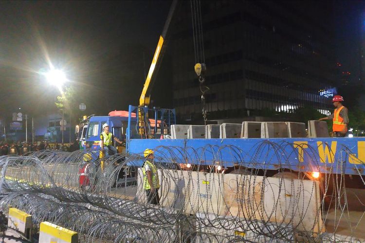 Petugas menurunkan separator beton MCB dari truk trailer guna menambah pengamanan di sekitar gedung Bawaslu RI Jakarta Pusat pada Jumat (24/5/2019) malam.