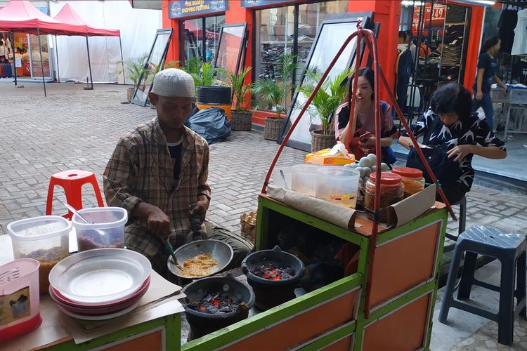 Pedagang kerak telor di Pekan Raya Jakarta tampak sibuk menyelesaikan pesanan pembeli.