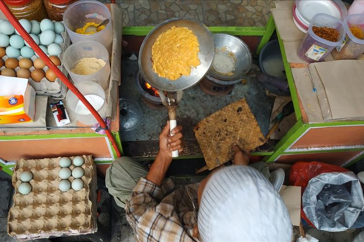 Pedagang kerak telor di Pekan Raya Jakarta tampak sibuk menyelesaikan pesanan pembeli.