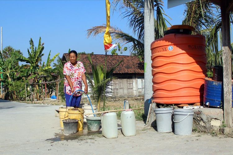 Warni (50), warga Dusun Marmoyo, Desa Marmoyo, Kecamatan Kabuh, Kabupaten Jombang, Jawa Timur, saat mengambil air di salah satu penampungan air di kampungnya, Rabu (26/6/2019). Di wilayah itu, krisis air bersih seringkali melanda saat musim kemarau.