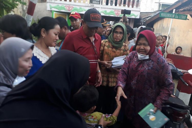 Wali Kota Surabaya Tri Rismaharini membagikan sejumlah buku kepada anak-anak usai meninjau lokasi kebakaran yang menghanguskan 16 rumah di Kelurahan Gundih, Kecamatan Bubutan, Surabaya, Rabu (10/7/2019).