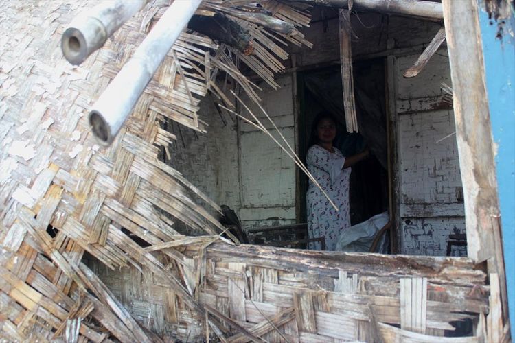 Seorang warga memerhatikan kondisi dinding rumah Latif (47) warga Cianjur, Jawa Barat yang jebol akibat sebagian atap bangunan ambruk diguyur hujan lebat