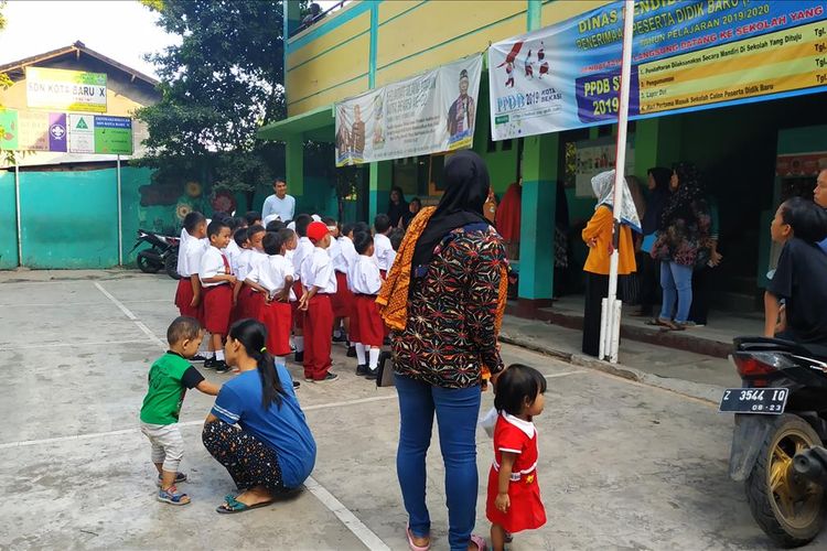 Para ibu siswa SDN Kota Baru X, Bekasi, masih setia memantau aktivitas buah hati mereka di hari kedua masuk sekolah, Selasa (16/7/2019). Beberapa di antaranya membawa serta anak-anak mereka yang masih balita.