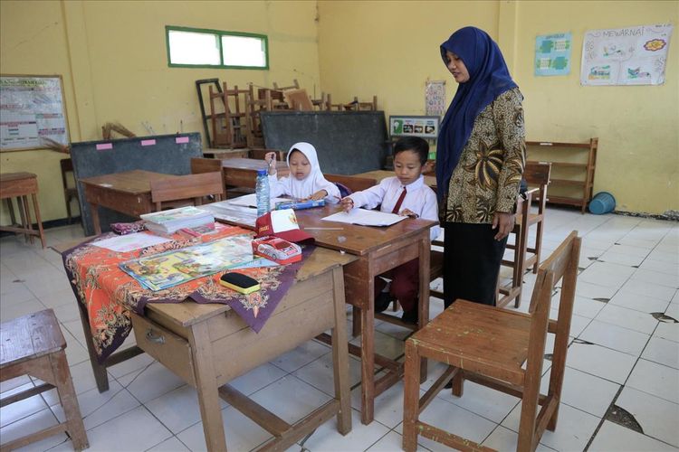 Salah satu guru SDN Sumberaji II, Sriami, membimbing 2 murid barunya, Selaa (16/11/2019). Sekolah dasar itu berada di Dusun Ngapus, Desa Sumberaji, Kecamatan Kabuh, Kabupaten Jombang, Jawa Timur.