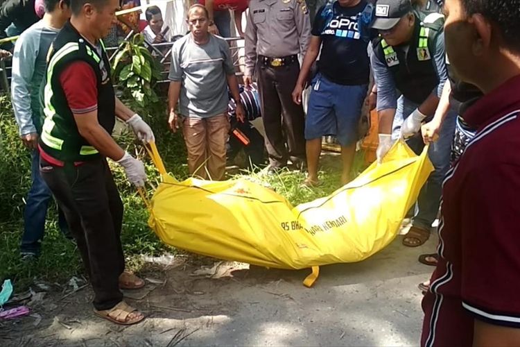 Polisi mengangkat kantong jenazah seorang PNS Dinas Pariwisata Provinsi Sultra, Abu Saila alias Aditya yang ditemukan tewas di selokan rumah warga di Kendari. (KIKI ANDI PATI/KOMPAS.com)