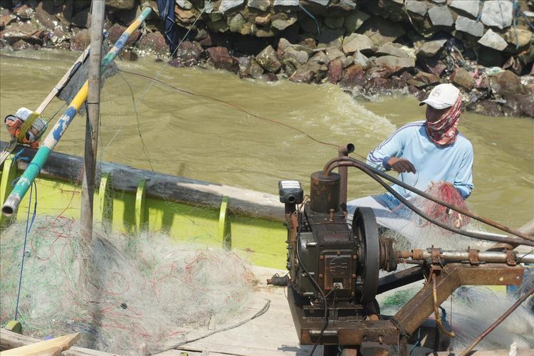 Seorang nelayan tengah membersihkan jaribg di Muara Cemarajaya, Kecamatan Cibuaya, Kabupaten Karawang, Senin (22/7/2019).