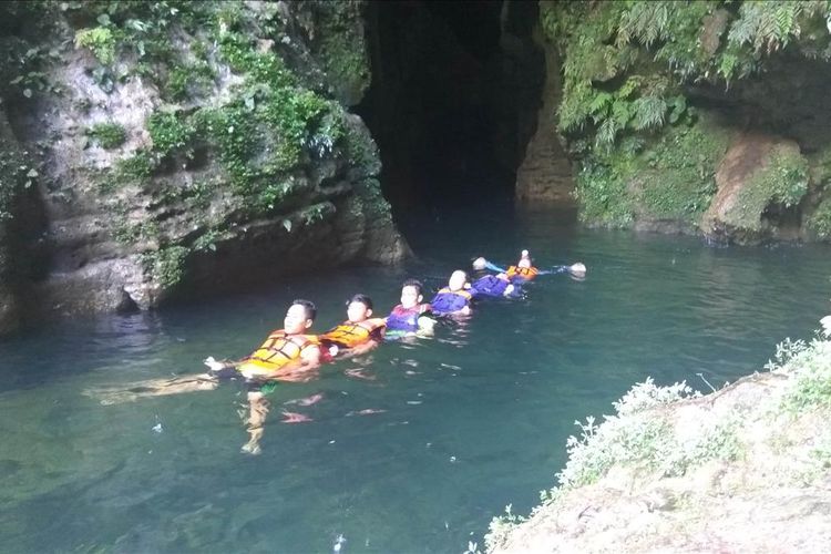 wisatawan asyik bermain body rafting di arus air yang berasal dari dalam gua.