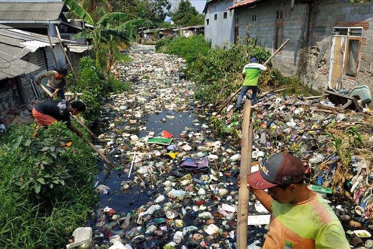 Warga bersama unsur koramil, kelurahan, dan Polsek Babelan membersihkan tutupan sampah di Kali Bahagia, Kabupaten Bekasi menggunakan peralatan sederhana, Selasa (30/7/2019).