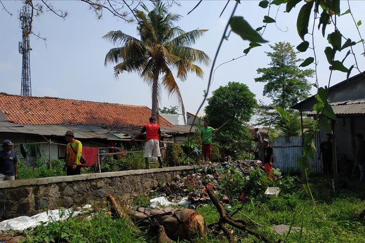 Warga bersama unsur koramil, Kelurahan, dan Polsek Babelan membersihkan tutupan sampah anorganik rumah tangga di Kali Bahagia, Kabupaten Bekasi, Selasa (30/7/2019).