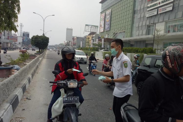 Petugas Dinas Kesehatan Riau membagikan masker saat Kota Pekanbaru diselimuti kabut asap karhutla, Selasa (30/7/2019). Dok. Diskes Riau