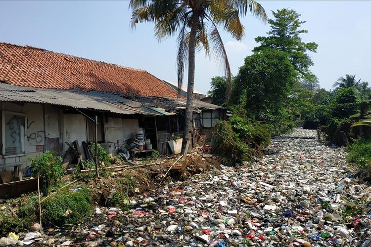 Bangunan liar di bantaran Kali Bahagia atau Kali Busa di Kecamatan Babelan, Kabupaten Bekasi yang alirannya tertutup sampah plastik.