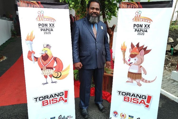 Anggota DPR Papua Ireneus Liku Bolly berfoto di antara banner logo dan maskot PON XX 2020 yang baru diluncurkan Gubernur Papua Lukas Enembe, di Kantor DPR Papua, Kamis (1/08/2019)