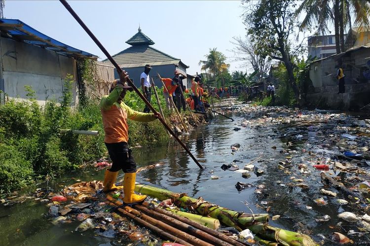 Seorang petugas kebersihan membersihkan tutupan sampah anorganik di Kali Bahagia, Kecamatan Babelan, Kabupaten Bekasi menggunakan rakit, Kamis (1/8/2019).