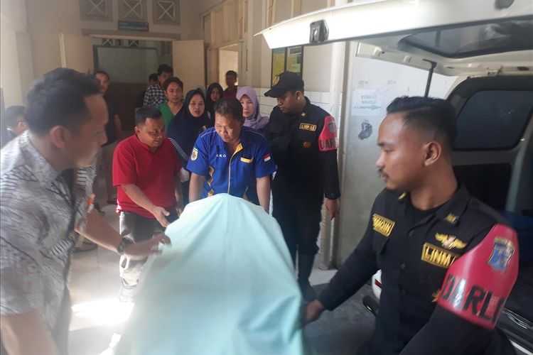 Jenazah peserta Surabaya Marathon 2019, Husnun Nadhor Djuraid, dibawa masuk ke ambulans untuk dipulangkan ke rumah duka di Malang, Jawa Timur, Minggu (4/8/2019).