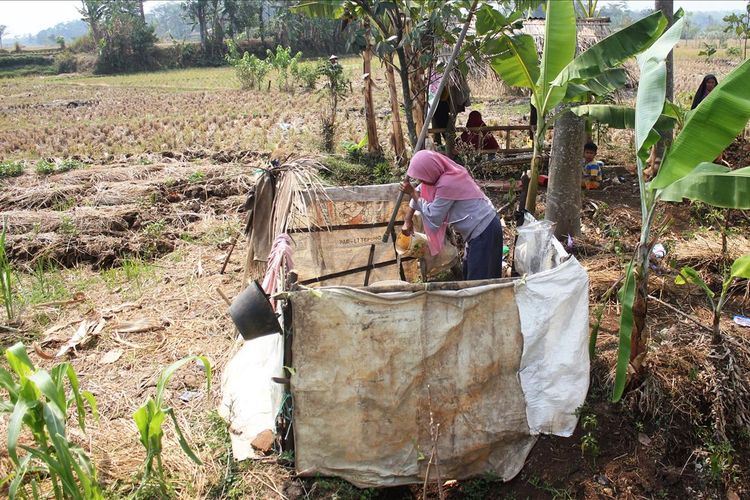 Seorang warga di Kp. Pasanggrahan, Cibeber, Cianjur, Jawa Barat melakukan aktivitas MCK di tengah areal pesawahan akibat kampung mereka yang tengah dilanda bencana kekeringan