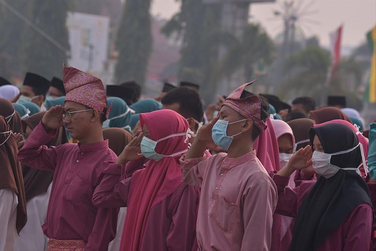 Peserta upacara HUT ke-62 Riau mengenakan masker, karena kabut asap karhutla cukup pekat menyelimuti wilayah Kota Pekanbaru, Riau, Jumat (9/8/2019).