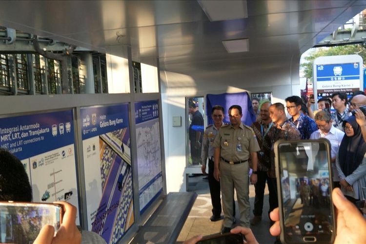 Gubernur DKI Jakarta Anies Baswedan memasang informasi soal rute transportasi umum di Halte Gelora Bung Karno (GBK), Jakarta Pusat, Selasa (13/8/2019).