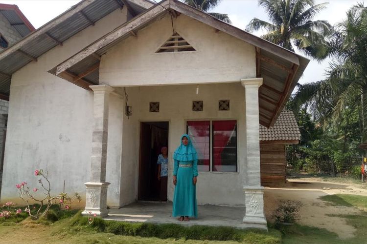 Ibu Asraf, Atik, berdiri di depan rumahnya yang sudah dibedah pemerintah setempat di Desa Bina Baru, Kecamatan Kampar Kiri Tengah, Kabupaten Kampar, Riau, Rabu (14/8/2019). Asraf salah satu Paskibraka nasional perwakilan Riau.