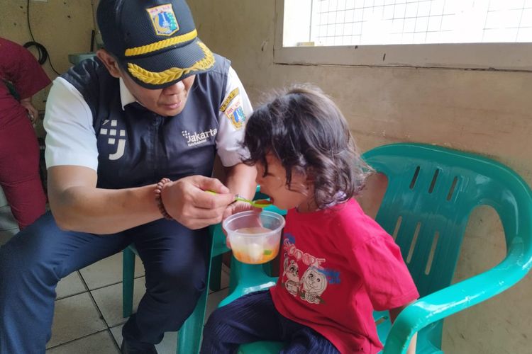 Kasie Kesehatan Masyarakat (Kesra) Kelurahan Bungur Asep Supriatna menyuapi anak stunting di wilayah Pos RW 05 Kelurahan Bungur, Senen, Jakarta Pusat, Rabu (22/11/2023). (KOMPAS.com/XENA OLIVIA)