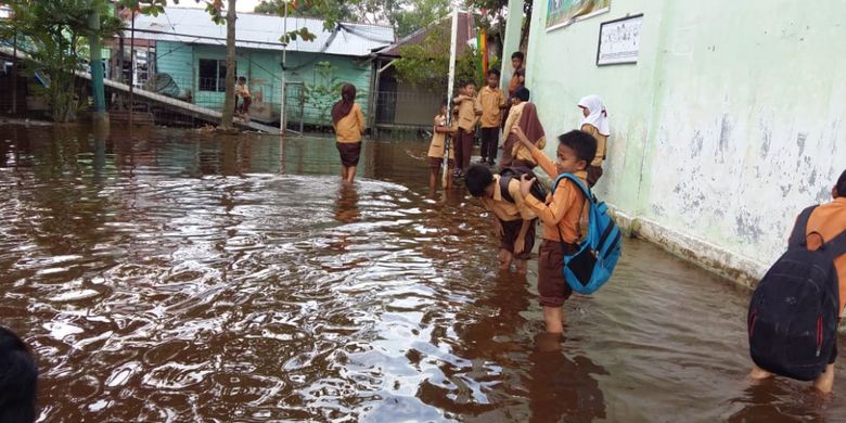 Anak-anak sekolah MIS Miftahudin di Kecamatan Rumbai Pesisir, Pekanbaru, Riau, mengarungi banjir yang melanda sekolahnya, Kamis (22/11/2018).