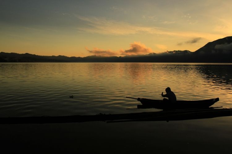 Seorang nelayan sedang mencari ikan saat matahari menyingsing di Danau Batur, yang merupakan danau di kaldera Gunung Batur pada ketinggian 1.050 mdpl. Permukaan air Danau Batur seluas 16.05 KM2, yang terletak di Kintamani, Kabupaten Bangli, Bali.