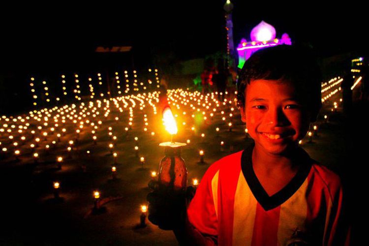 Seorang anak menikmati tradisi Tumbilotohe atau malam pasang lampu di Gorontalo. Tradisi ini dilakukan pada 3 hari menjelang Hari Raya Idul Fitri