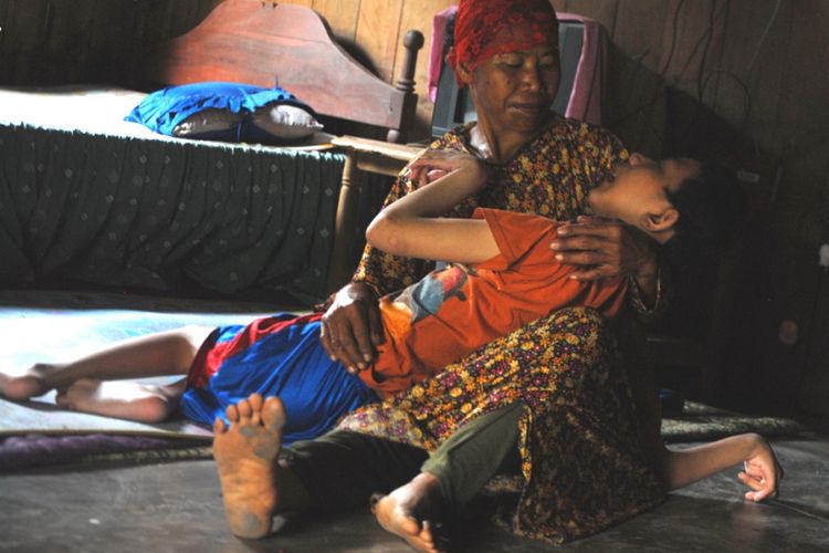 Tatapan mata Jumini (45‎) terlihat kosong saat memangku anak bungsunya Triyono (18), di dalam ruang tamu rumahnya di Desa Tanggungharjo, Kecamatan Grobogan, Kabupaten Grobogan, Jawa Tengah, Selasa (8/8/2017) sore.