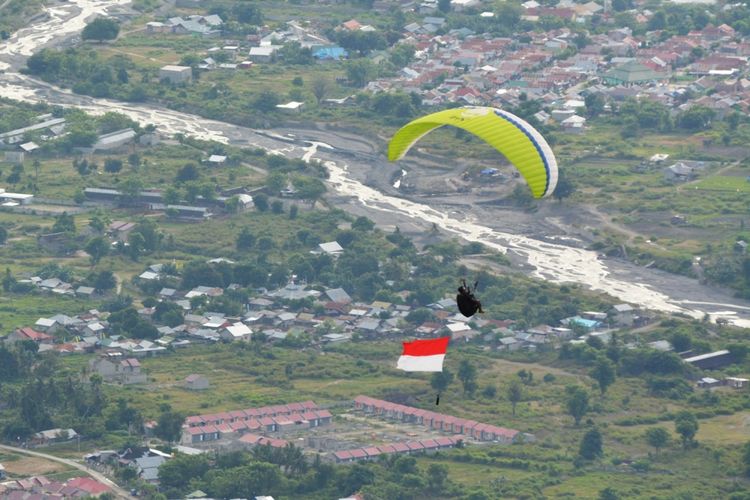 Seorang atlet paralayang terbang sambil membawa bendera Merah Putih di Pegunungan Matantimali Desa Wayu, Kinovaro, Sigi, Sulawesi Tengah, Kamis (17/8/2017). Aksi itu dilaksanakan sebagai bagian dari peringatan HUT ke-72 RI. 