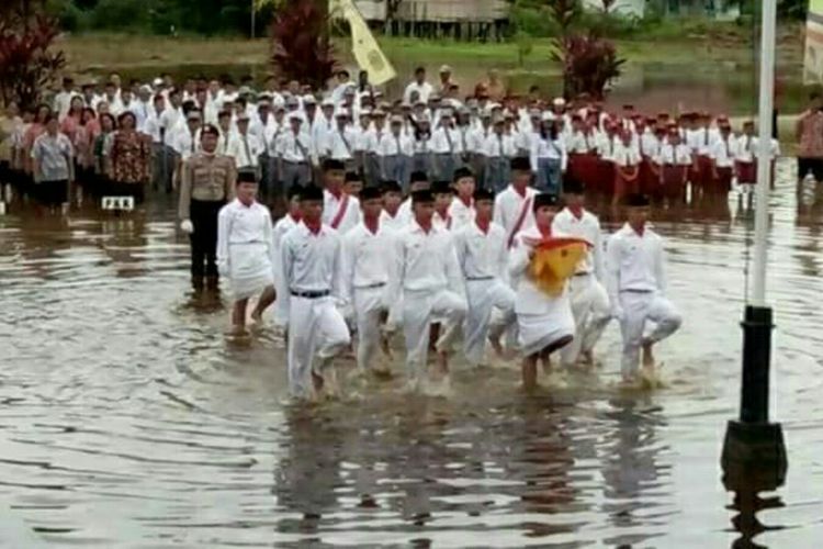 Suasana upacara bendera peringatan HUT ke 72 RI di tengah kondisi banjir di halaman Kantor Camat Bika, Kabupaten Kapuas Hulu, Kalimantan Barat (17/8/2017)