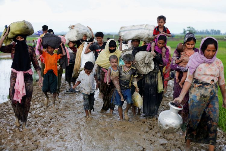 Sekelompok pengungsi Rohingya berjalan di jalan berlumpur setelah melewati perbatasan Bangladesh-Myanmar di Teknaf, Bangladesh, Jumat (1/9/2017).