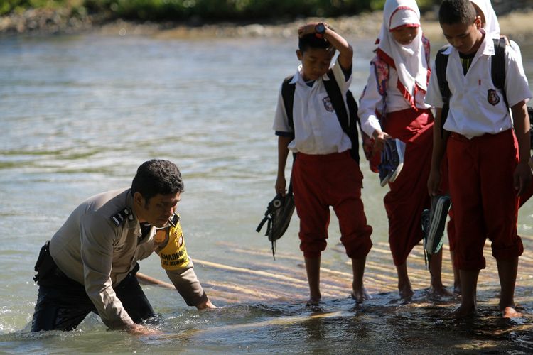 Bhabinkamtibmas Desa Mongiilo Utara Aipda Ismet Ishak (kiri) membantu siswa yang menaiki rakit penyeberangan untuk berangkat ke Sekolah Dasar (SD) Negeri 1 Bulango Ulu, Kabupaten Bone Bolango, Gorontalo, Selasa (5/9/2017). Sebanyak 30 siswa dari Mongiilo Utara dan Ilomata harus berjalan kaki sejauh 2-4 kilometer dari rumah mereka dan menyeberangi sungai untuk berangkat ke sekolah yang berada di Mongiilo Induk. 