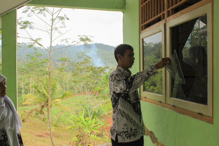 Salah satu guru SDN 2 Lebakwangi, Ardi Hermawan menunjukkan kaca yang pecah dirusak orang tak dikenal, Minggu (24/9/2017) dini hari.