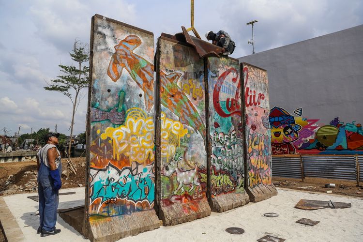 Seorang pekerja melakukan pemasangan patung baja di kawasan Ruang Publik Terpadu Ramah Anak (RPTRA) dan Ruang Terbuka Hijau (RTH) Kalijodo, Jakarta Barat, Selasa (26/9/3017). Karya seni instalasi ini bernama Patung Menembus Batas terdiri dari empat pecahan tembok Berlin dan 14 patung baja hasil karya dari seniman Teguh Osternik.