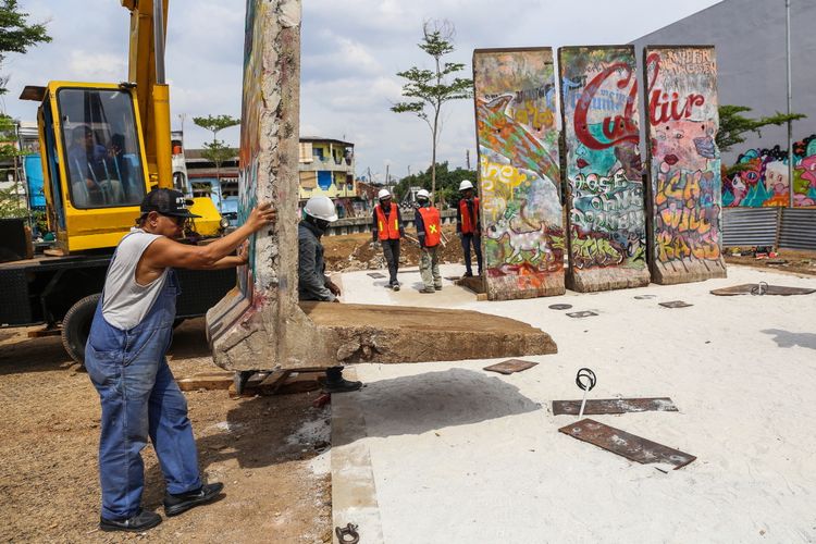 Seniman Teguh Osternik (kiri) melakukan pemasangan batu pecahan tembok berlin di kawasan Ruang Publik Terpadu Ramah Anak (RPTRA) dan Ruang Terbuka Hijau (RTH) Kalijodo, Jakarta Barat, Selasa (26/9/3017). Karya seni instalasi ini bernama Patung Menembus Batas terdiri dari empat pecahan tembok Berlin dan 14 patung baja hasil karya dari seniman Teguh Osternik.
