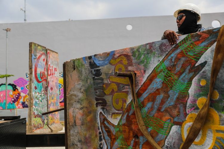 Seorang pekerja melakukan pemasangan batu pecahan tembok berlin di kawasan Ruang Publik Terpadu Ramah Anak (RPTRA) dan Ruang Terbuka Hijau (RTH) Kalijodo, Jakarta Barat, Selasa (26/9/3017). Karya seni instalasi ini bernama Patung Menembus Batas terdiri dari empat pecahan tembok Berlin dan 14 patung baja hasil karya dari seniman Teguh Osternik.