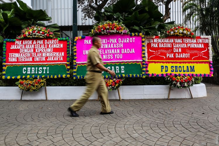 Warga melintas di antara karangan bunga yang ditujukan untuk Basuki Tjahaja Purnama atau Ahok dan Djarot Saiful Hidayat di kompleks Balai Kota DKI Jakarta, Senin (9/10/2017). Karangan bunga tersebut berisi ucapan terima kasih dari warga atas kepemimpinan Basuki dan Djarot selama berpasangan menjadi gubernur dan wakil gubernur DKI Jakarta.